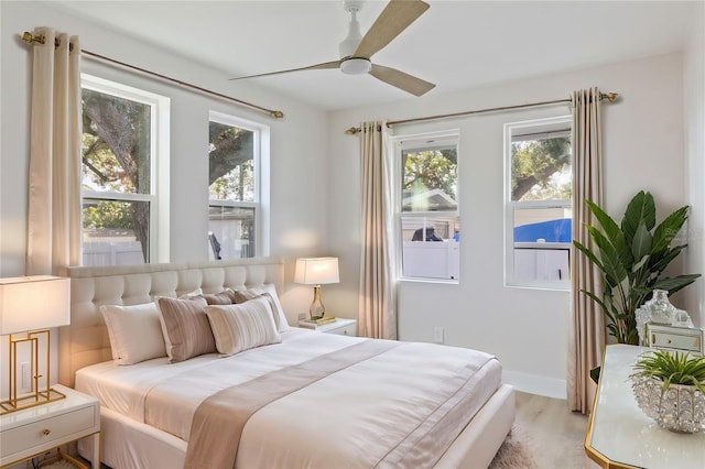 bedroom with ceiling fan, multiple windows, and light wood-type flooring