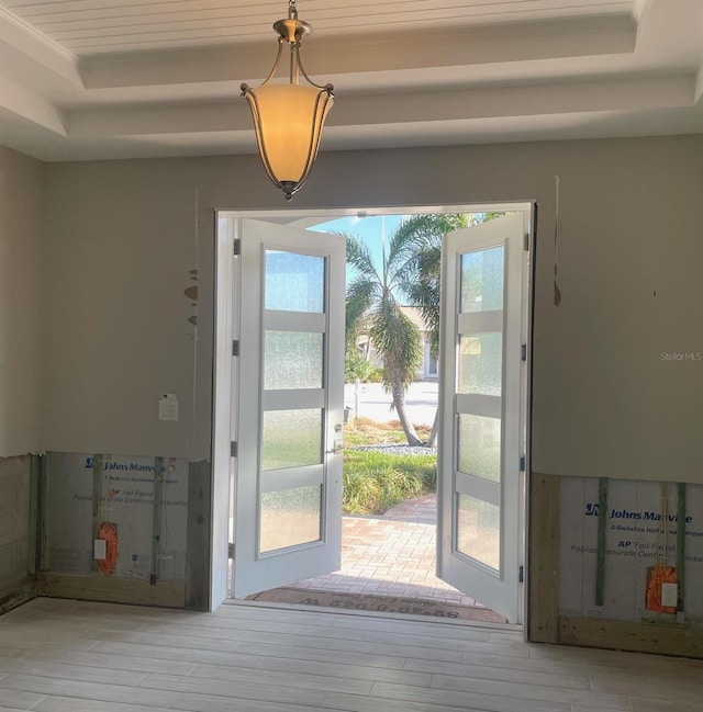 doorway with a tray ceiling, french doors, and light hardwood / wood-style floors