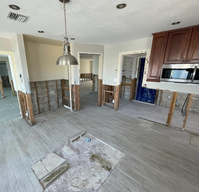 unfurnished dining area with a textured ceiling and light wood-type flooring