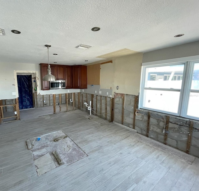 kitchen featuring decorative light fixtures, a textured ceiling, and light hardwood / wood-style flooring