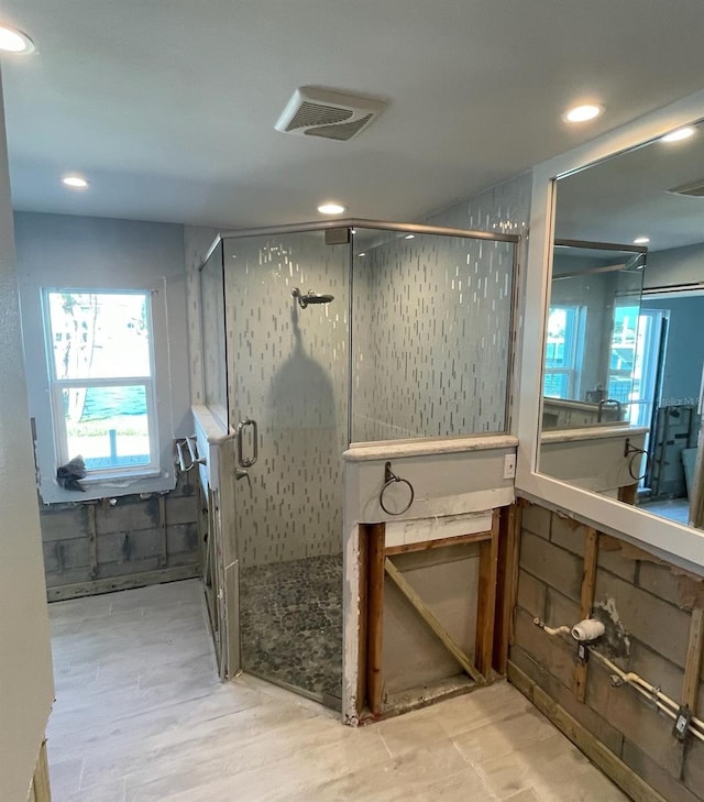 bathroom with wood-type flooring and an enclosed shower