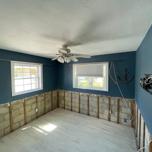 spare room with ceiling fan, light hardwood / wood-style floors, and a textured ceiling