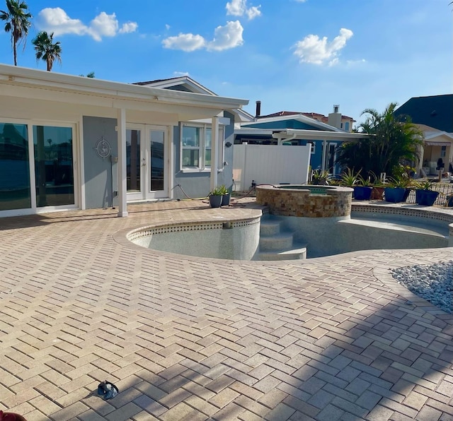 view of swimming pool with an in ground hot tub, a patio, and french doors