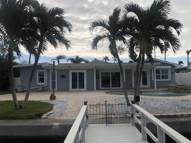 rear view of property featuring a patio and a pool with hot tub