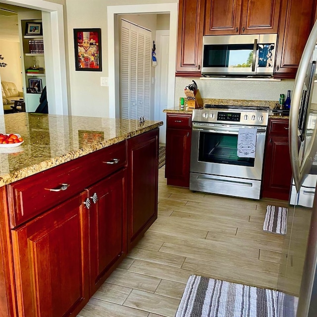 kitchen with light stone countertops, light wood-type flooring, and appliances with stainless steel finishes