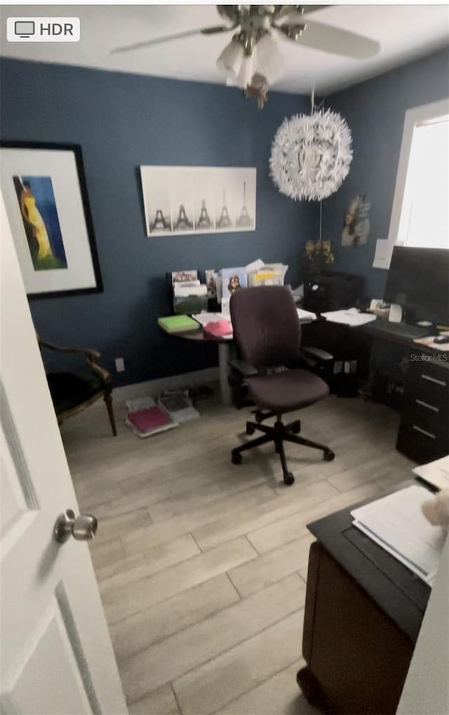 office featuring ceiling fan with notable chandelier and light hardwood / wood-style flooring