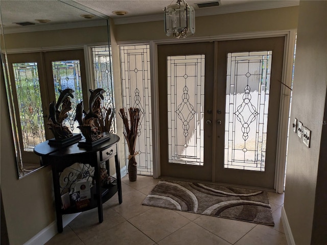 tiled entrance foyer featuring a wealth of natural light, french doors, and ornamental molding