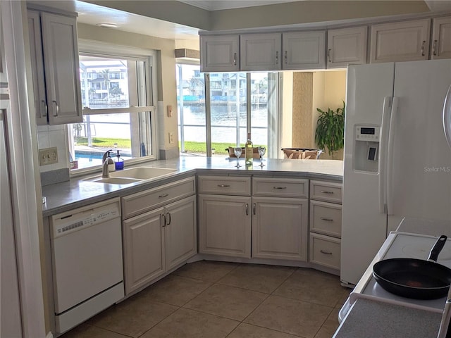 kitchen with white appliances, sink, light tile patterned floors, white cabinetry, and kitchen peninsula