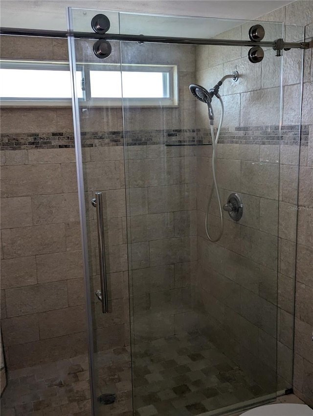 bathroom with toilet and a shower with shower door