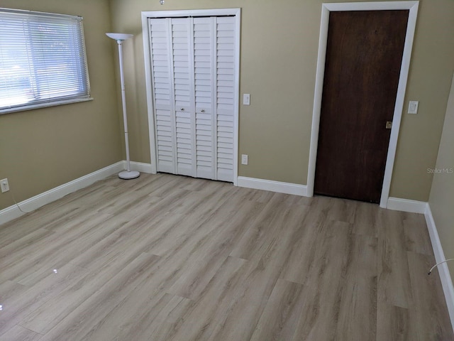 unfurnished bedroom with light wood-type flooring and a closet