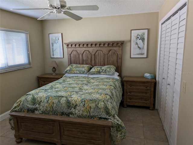 bedroom featuring a textured ceiling, a closet, tile patterned floors, and ceiling fan