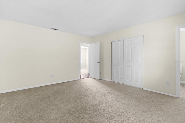 unfurnished bedroom featuring light carpet and a closet