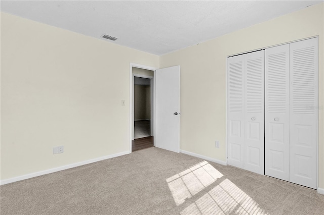 unfurnished bedroom with a closet and light colored carpet