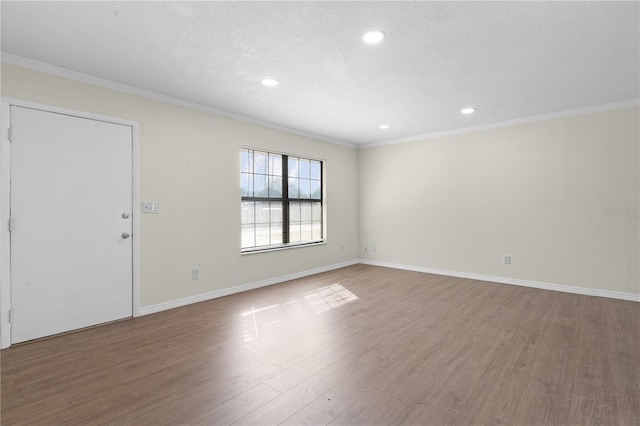 spare room with a textured ceiling, hardwood / wood-style flooring, and ornamental molding