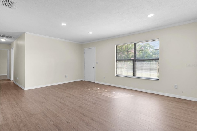 empty room with hardwood / wood-style floors, a textured ceiling, and ornamental molding