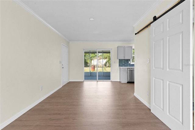 unfurnished living room with a barn door, ornamental molding, and hardwood / wood-style flooring