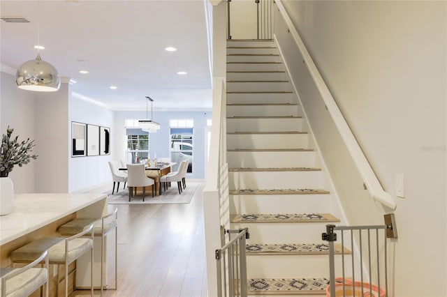 stairs featuring hardwood / wood-style floors and crown molding