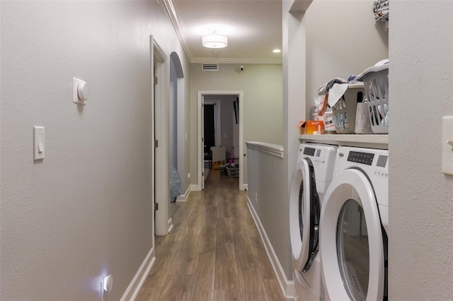 laundry room featuring dark hardwood / wood-style flooring, crown molding, and washer and clothes dryer