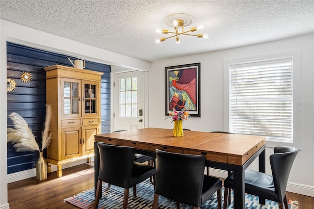 dining space with a textured ceiling, dark hardwood / wood-style floors, and an inviting chandelier