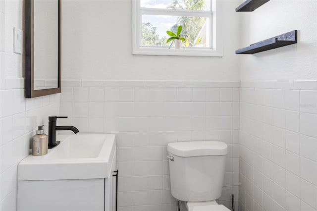 bathroom with vanity, toilet, and tile walls