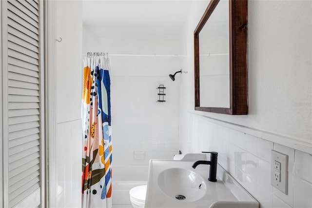 full bathroom featuring shower / bath combo, toilet, sink, and tile walls