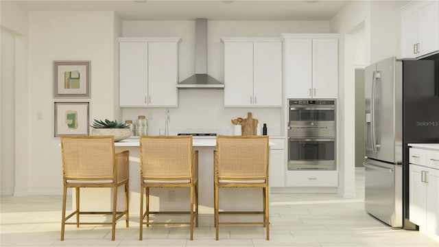 kitchen with appliances with stainless steel finishes, a breakfast bar area, wall chimney exhaust hood, and white cabinets