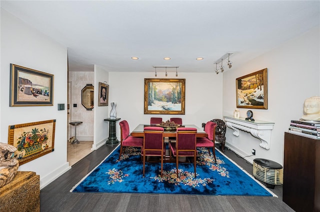 dining area with rail lighting and dark hardwood / wood-style floors