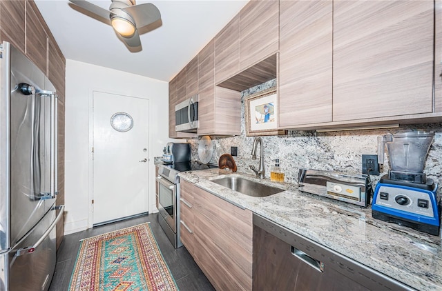 kitchen featuring sink, ceiling fan, stainless steel appliances, light stone countertops, and backsplash