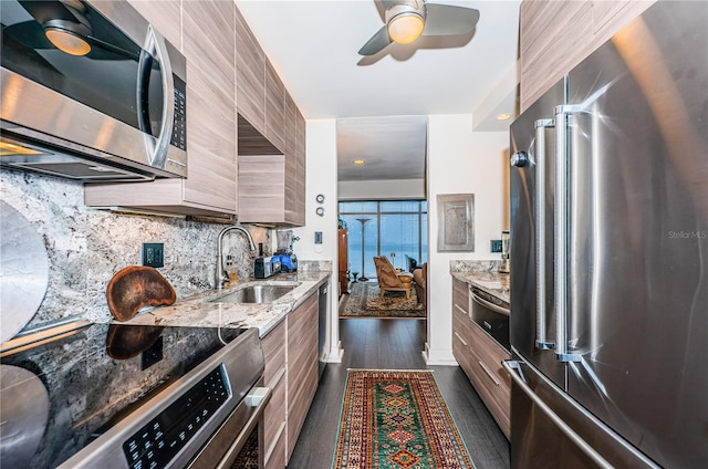 kitchen featuring dark wood-type flooring, sink, light stone counters, appliances with stainless steel finishes, and decorative backsplash