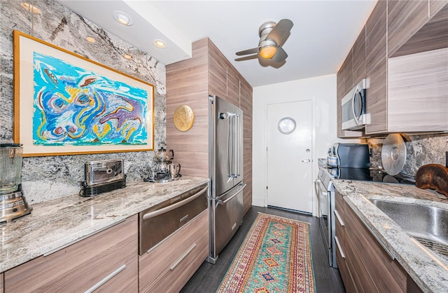 kitchen with light stone counters, appliances with stainless steel finishes, sink, and backsplash