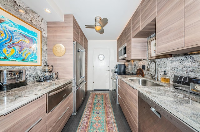 kitchen featuring appliances with stainless steel finishes, sink, decorative backsplash, ceiling fan, and light stone counters