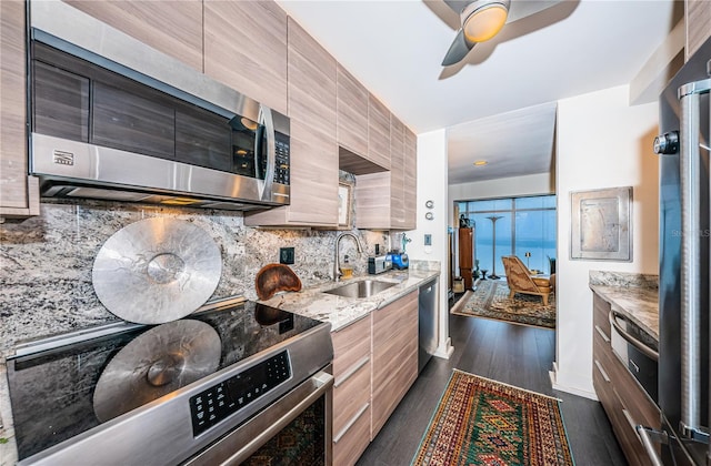 kitchen with dark wood-type flooring, sink, tasteful backsplash, stainless steel appliances, and light stone countertops