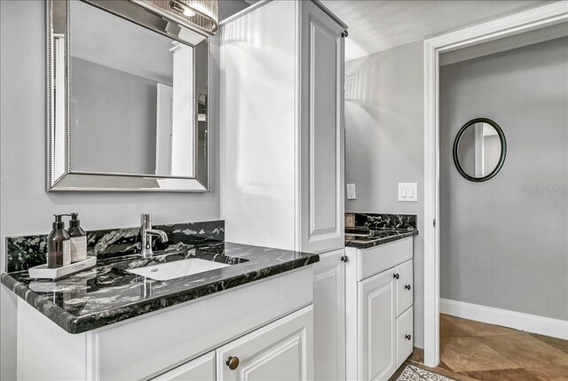 bathroom with two vanities, a sink, and baseboards