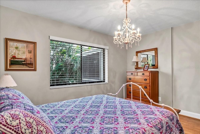 bedroom with a notable chandelier, baseboards, and wood finished floors