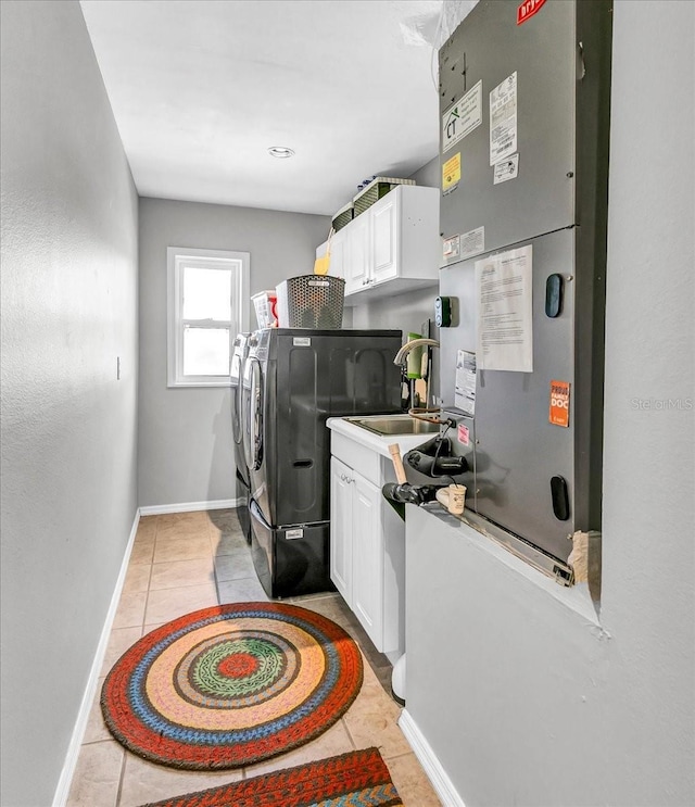 washroom with light tile patterned floors, cabinet space, baseboards, separate washer and dryer, and a sink