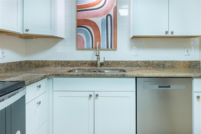 kitchen with stainless steel appliances, white cabinetry, dark stone counters, and sink