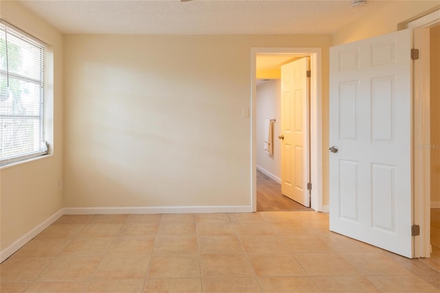 unfurnished room with light tile patterned floors and a textured ceiling