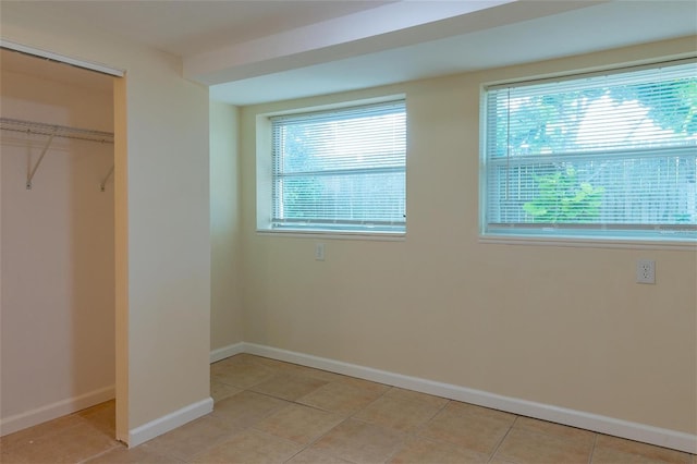 unfurnished bedroom with a closet, multiple windows, and light tile patterned flooring