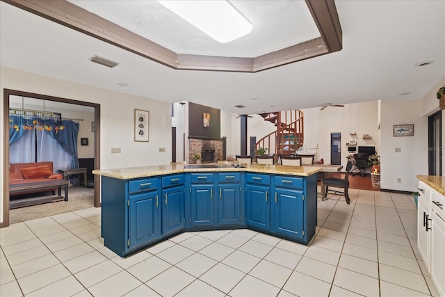 kitchen featuring white cabinets, a fireplace, a kitchen island, and blue cabinets