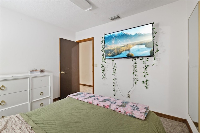 bedroom featuring a textured ceiling and light colored carpet