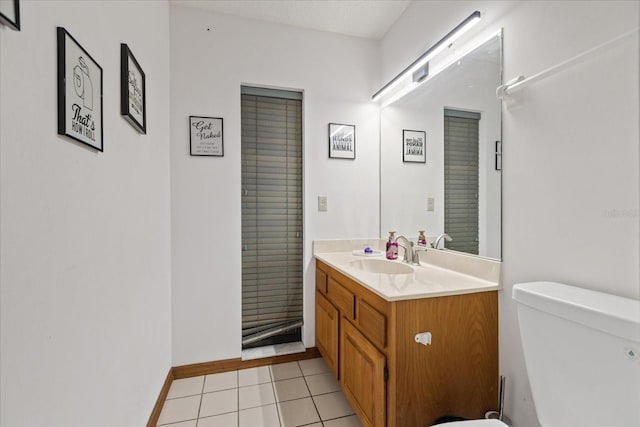 bathroom with toilet, vanity, and tile patterned floors