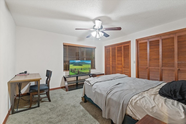 carpeted bedroom featuring ceiling fan, a textured ceiling, and two closets