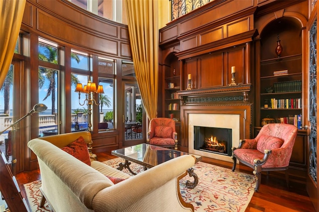 living area with built in features, a high ceiling, wood walls, and dark wood-type flooring