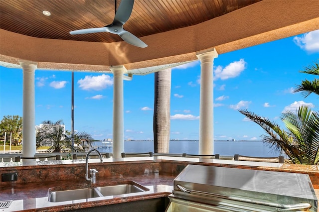 view of patio featuring exterior kitchen, sink, ceiling fan, and a water view