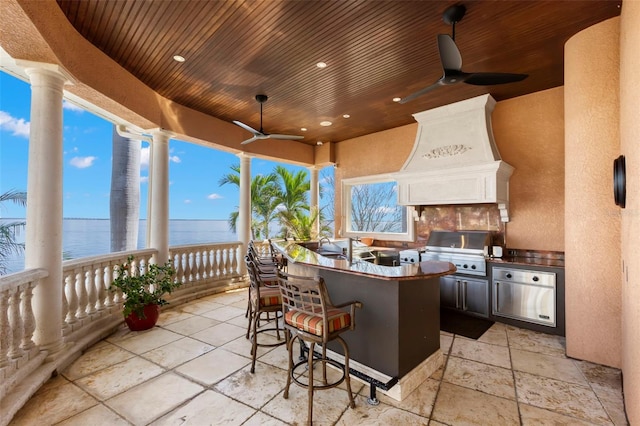 view of patio featuring area for grilling, a water view, an outdoor bar, and ceiling fan