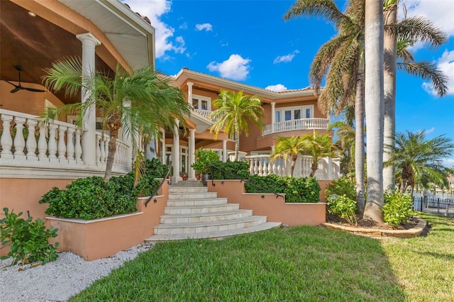 101 12th St E, Tierra Verde, FL 33715 - view of front of house with stairway, a front yard, stucco siding, and a tile roof