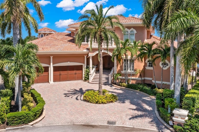 101 12th St E, Tierra Verde, FL 33715 - mediterranean / spanish home featuring stucco siding, curved driveway, a tile roof, and an attached garage