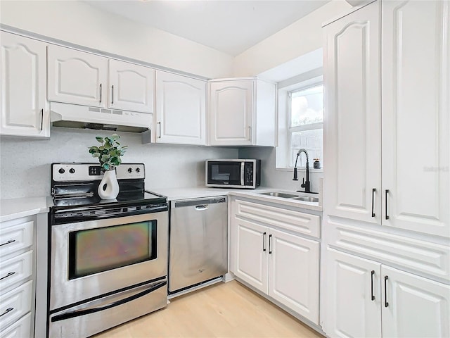 kitchen with sink, light hardwood / wood-style flooring, appliances with stainless steel finishes, tasteful backsplash, and white cabinetry