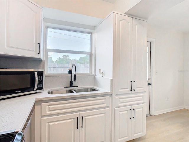 kitchen featuring stove, light hardwood / wood-style floors, white cabinetry, and sink