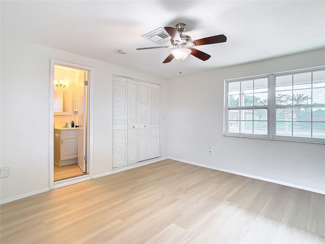 unfurnished bedroom featuring ceiling fan, ensuite bath, light hardwood / wood-style flooring, and a closet